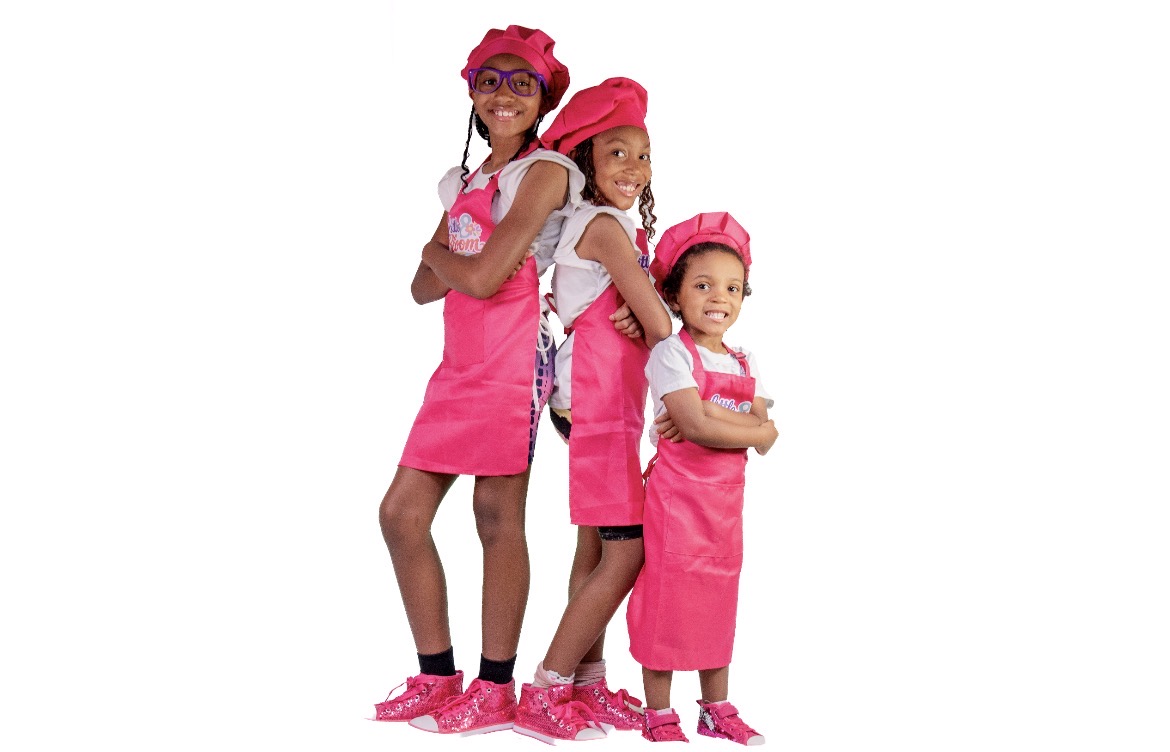 The three Bloom Bakers — Autumn Marie, Avery Melody and Angela Michelle — in their pink chef hats and aprons, the real faces behind Little 8 Bloom